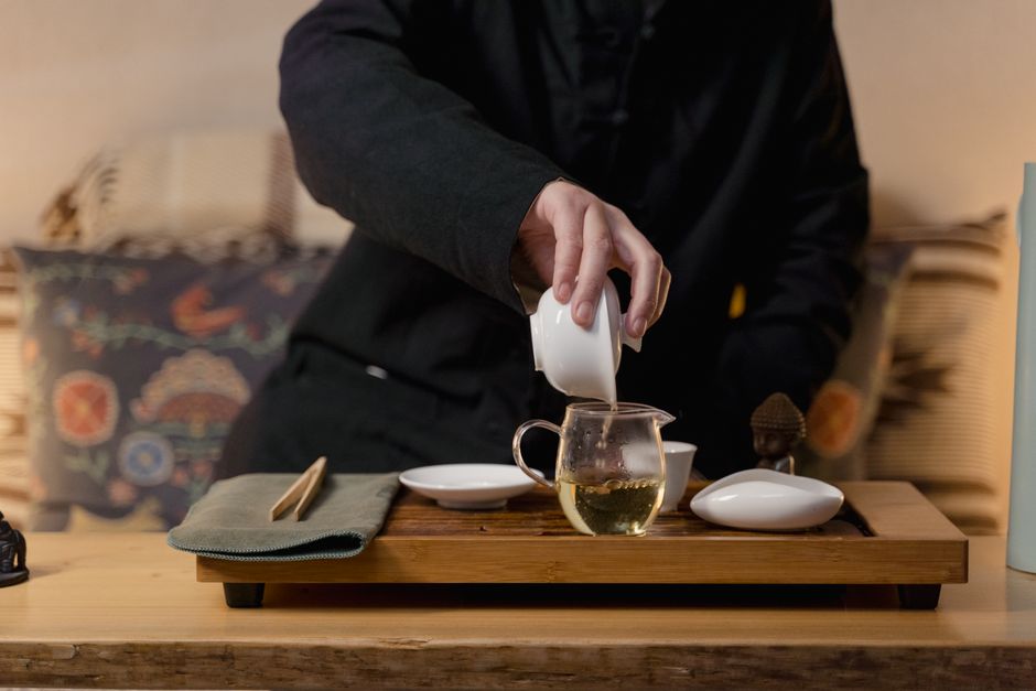 A person performing a traditional Chinese tea ceremony with a gaiwan and cha hai set.